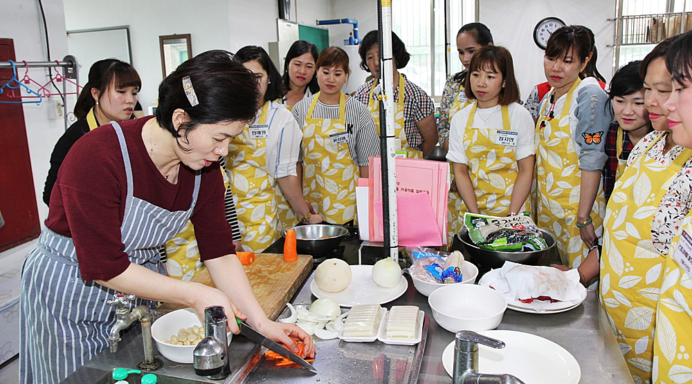 =우선미 평생학습관 강사(왼쪽)가 결혼이민여성 교육생들에게 요리 실습교육을 실시하고 있다. / 충북농협 제공<br>