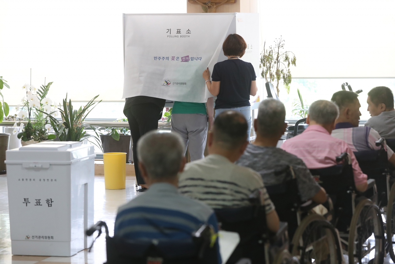 6·13지방선거 기관·시설 거소투표가 실시된 5일 오후 서울 은평구 시립평화로운집에 마련된 투표소에서 중증장애인이 선거관리위원회 직원들의 도움을 받아 소중한 한 표를 행사하고 있다. / 뉴시스