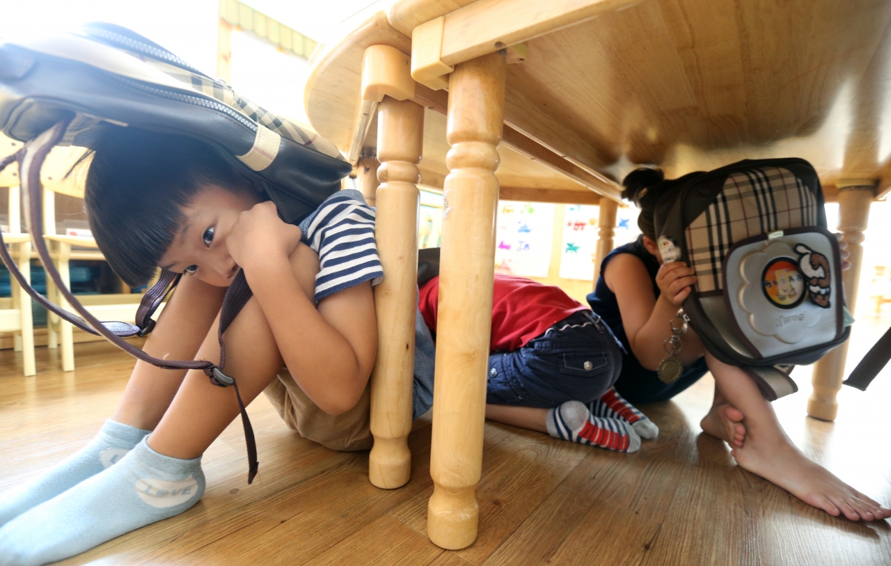 '제408차 민방위의 날'을 맞아 지진 대피훈련이 실시된 12일 청주 산남유치원 아이들이 지진경보가 발령되자 책상 밑에서 만일의 사태에 대비하고 있다. / 신동빈