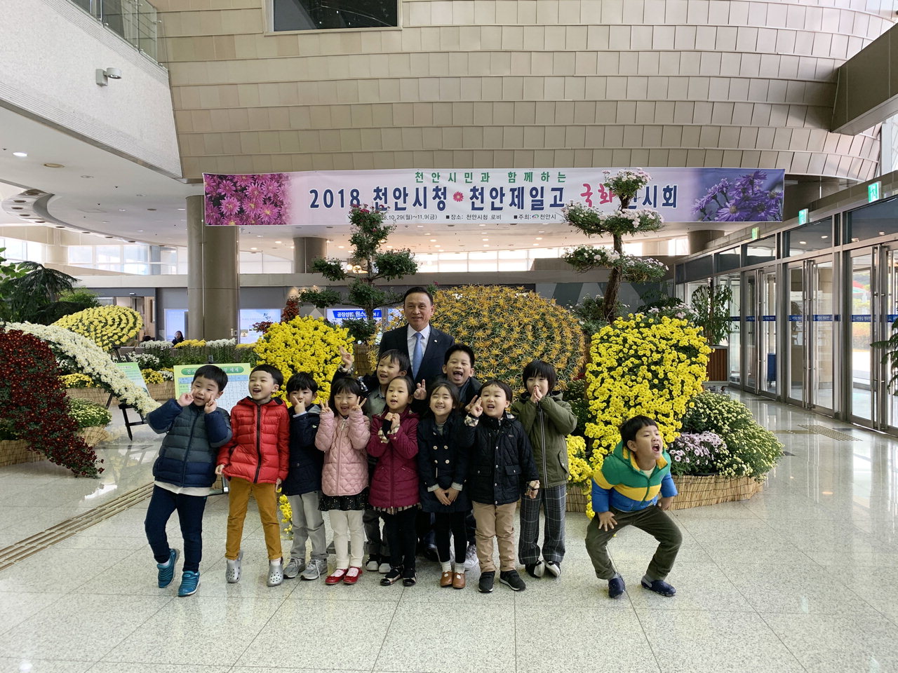 구본영 천안시장이 천안시청사 1층 로비에서 열리고 있는 ‘2018 시민과 함께 공감하고 누리는 국화전시회’를 보러온 아이들과 기념사진을 찍고 있다. / 천안시