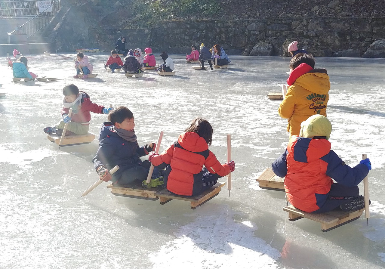 겨울방학 금산산림문화타운 얼음썰매장을 찾은 아이들이 썰매를 타고 있다.<혹은> 겨울방학 금산산림문화타운 얼음썰매장을 찾은 아이들이 컬링 경기를 하고 있다. / 금산군