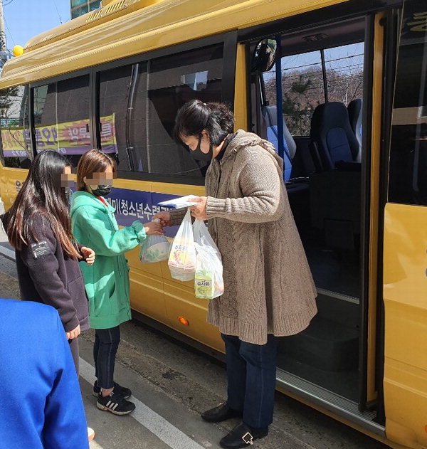 돌봄교사가 돌봄 대상 청소년들에게 간식 및 학습지원 과제물 나눠주고 있다. / 옥천군 제공