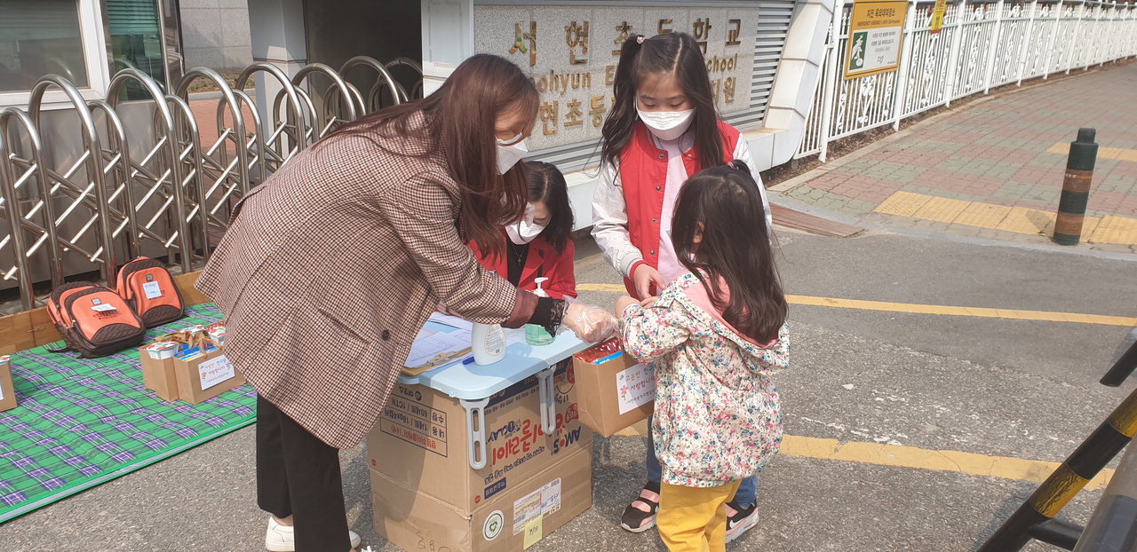 청주 서현초 병설유치원 교사가 학부모와 함께 온 유아에게 놀이자료를 배부하고 있다. /서현초 병설유치원 제공