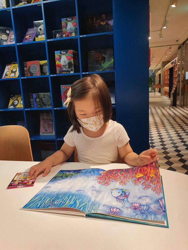 어린이가 중고서점에서 그림책을 보고 있다.