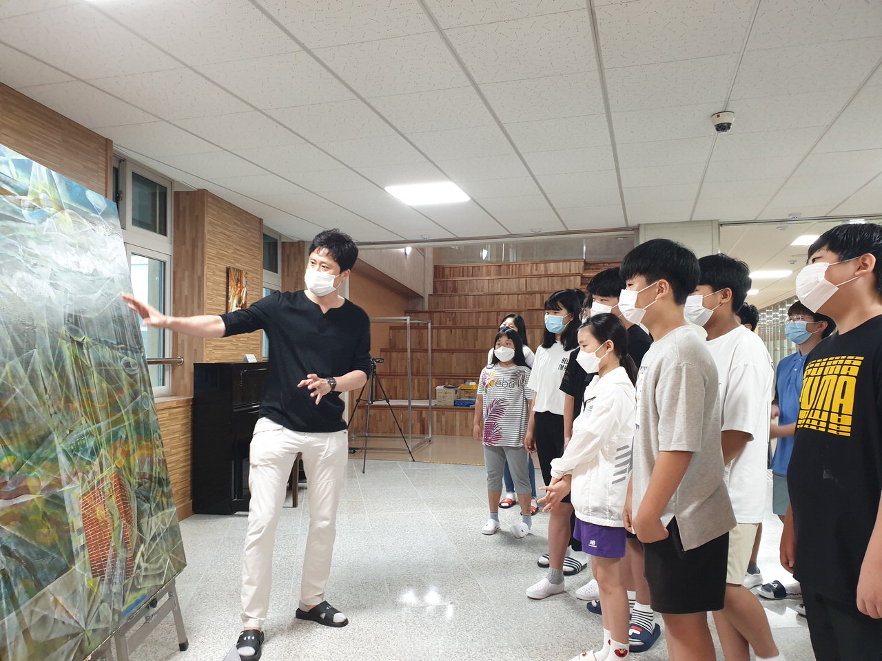 진천상신초등학교 학생들이 버스킹 무대에 전시된 작가의 그림을 사윤택 작가와 함께 감상하며 이야기 하고 있다. / 진천교육청 제공