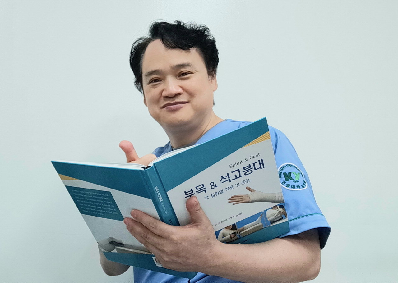 김영철 건양대병원 석고치료사가 자신의 책을 들고 기념사진을 찍고 있다. / 건양대병원 제공