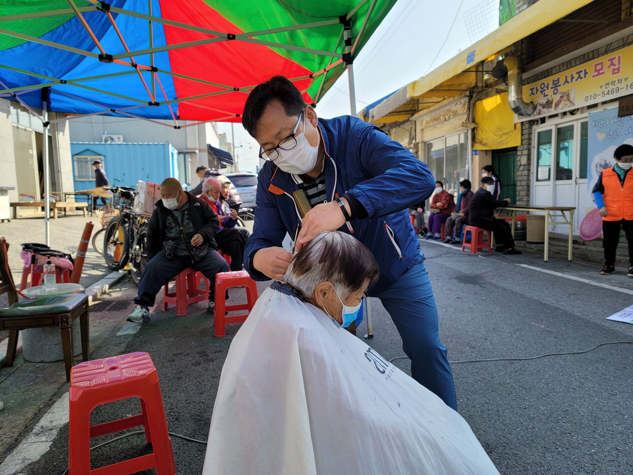 이상희 경위가 무료급식소인 '재성이네 나눔쉼터' 앞에서 급식을 받으러온 사람들에게 머리를 깎아주고 있다.