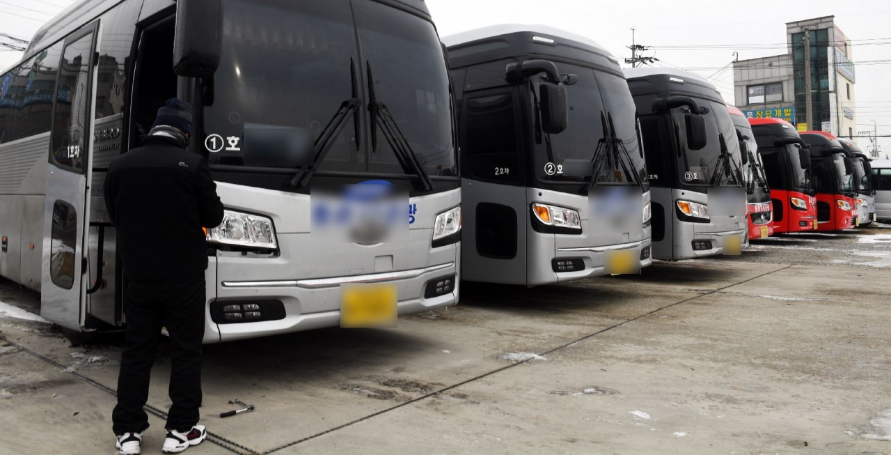 10일 청주시 서원구의 전세버스 회사 주차장에서 직원이 차량을 정비하고 있다. 코로나19 여파로 전세버스 운행이 크게 감소하면서 주차장을 지키는 버스가 늘고 있다. /김명년