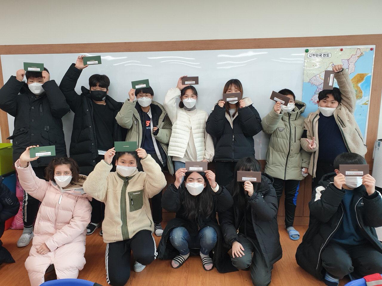 진천 이월초등학교 졸업생들이 총동문회 선배들이 전달한 백화점 상품권을 들어보이며 기뻐하고 있다. / 진천교육청 제공