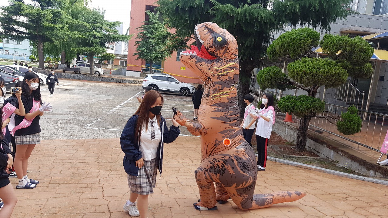 영동중 교사가 공룡 분장을 하고 등교하는 학생들을 맞이하고 있다. / 영동중학교 제공
