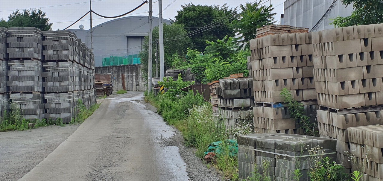 복개한 하천 부지에 건축자재들이 쌓여 농로 양쪽을 막고 있는 모습. /박건영
