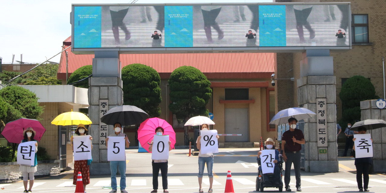 충북기후위기비상행동이 지난 7월 21일 충북도청 서문 앞에서 우산을 활용한 퍼포먼스를 벌이며 충북도에 탄소 50% 감축을 요구하고 있다. / 정세환