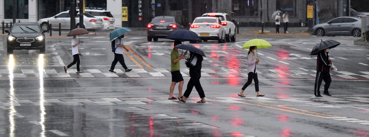 태풍 '오마이스'의 영향으로 충북지역에 많은 양의 비가 내린 23일 청주시 청원구의 한 횡단보도에서 시민들이 우산을 쓰고 걸어가고 있다. /김명년