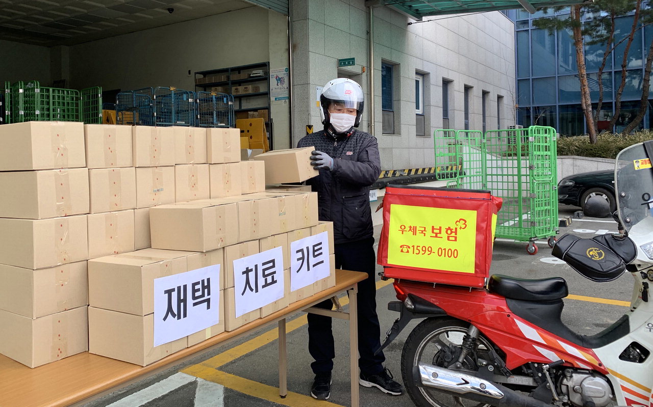 대전 둔산우체국 집배원이 16일 코로나19 재택치료자들에게 배송할 재택치료키트 상자를 싣고 있다. / 우정사업본부