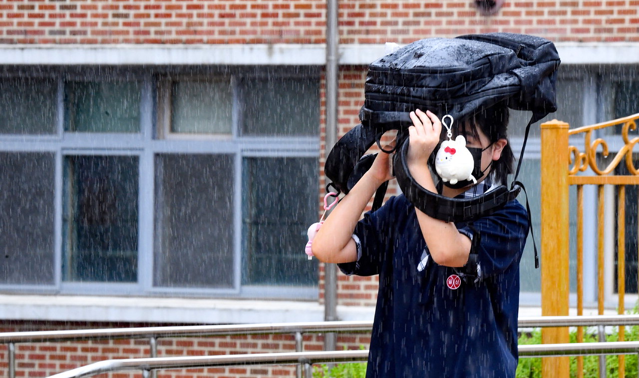 비가 내린 11일 청주 일신여자고등학교에서 한 학생이 가방으로 비를 막으며 발걸음을 재촉하고 있다. /김명년