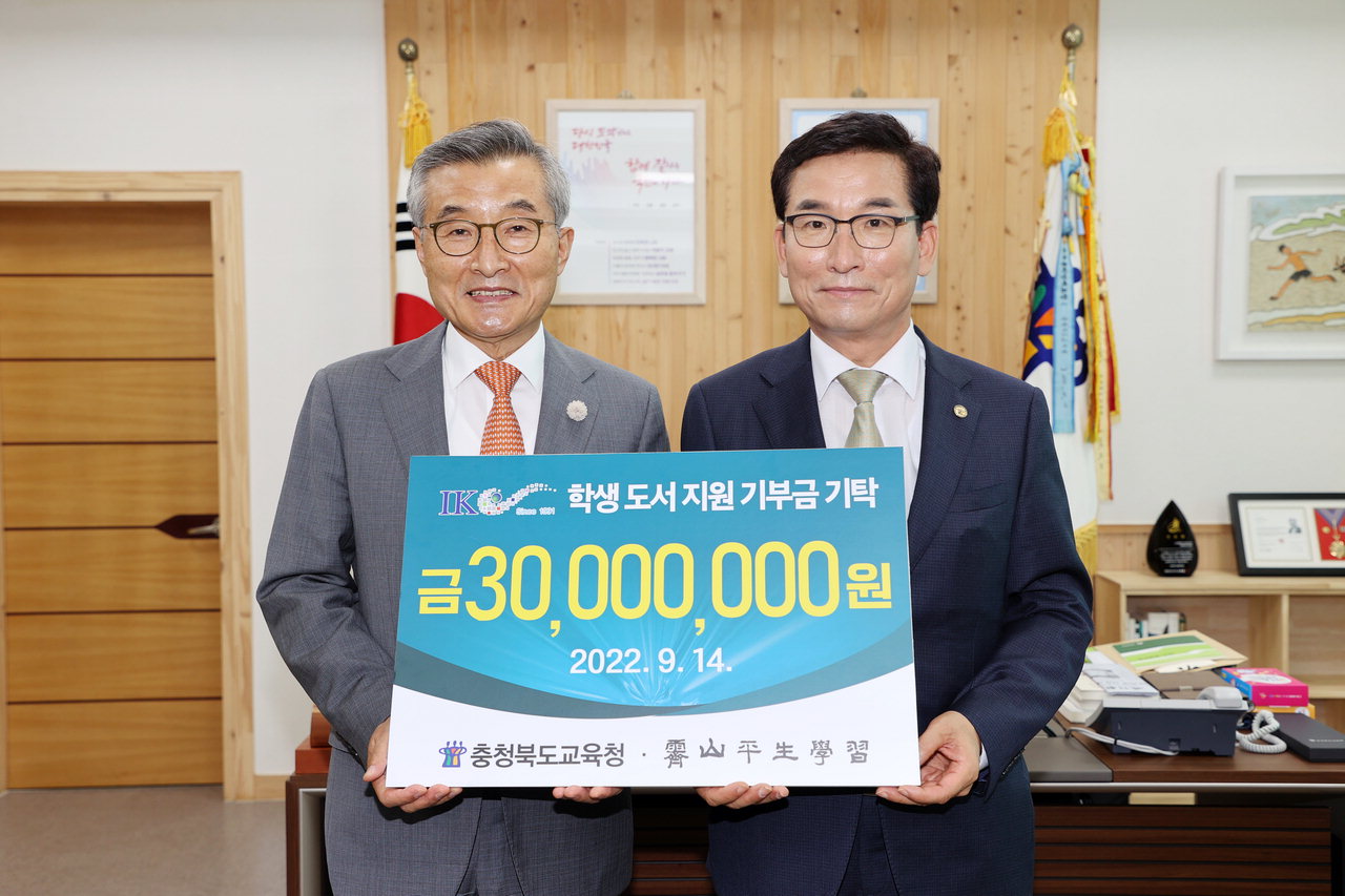김상문(왼쪽) (주)아이케이 회장이 윤건영 충북도교육감에 3천만 원을 전달하며 도서구입에 사용해 달라고 당부했다.