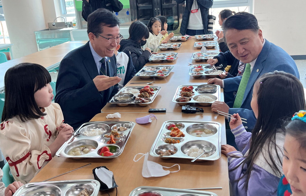 윤건영(왼쪽) 교육감과 김영환 지사가 단재초에서 배식을 받은 뒤 2학년 학생들과 함께 점심식사를 하고 있다. / 이지효