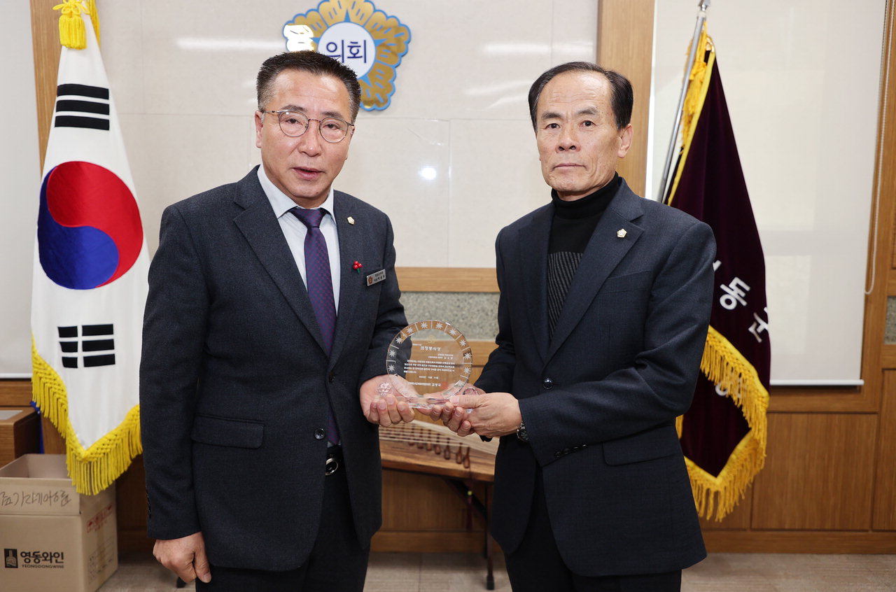 이승주 영동군의회 의장이 김오봉 산업위원장(오른쪽)에게 상패를 전수하고 있다. / 영동군의회