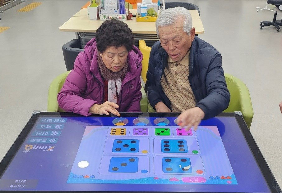 노인들이 멀티미디어 학습장치를 이용해 인지테스트를 하는 모습