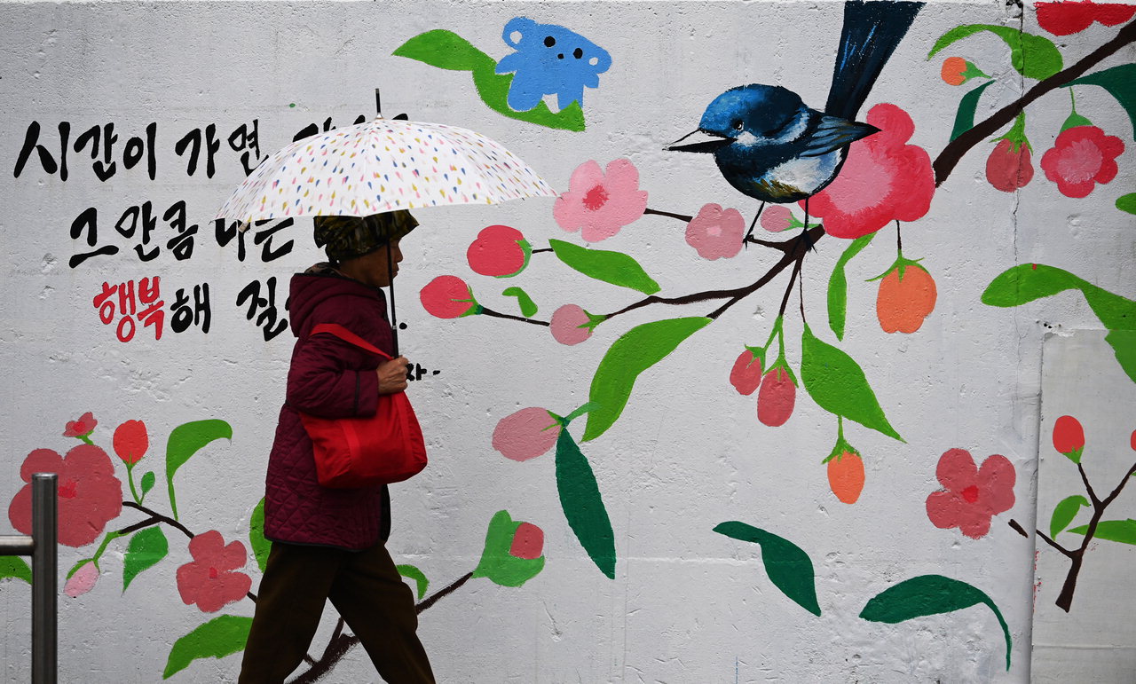 봄비가 내린 5일 청주시 청원구에 꽃 벽화가 그려진 거리에서 우산을 쓴 어르신이 지나가고 있다. /윤재원