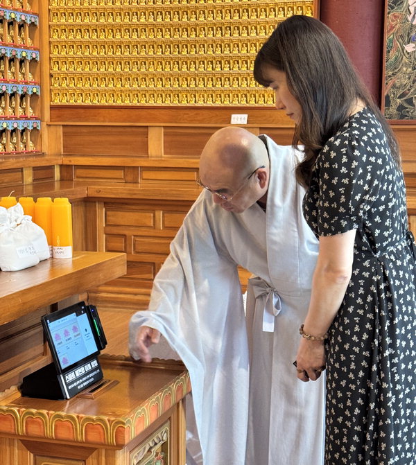 태블릿(KT 하이오더) 불전함을 주지스님과 방문객이 사용하고 있는 모습 / KT 충남/충북광역본부