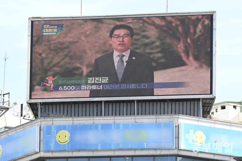 ▲ 김진균 청주시체육회장이 ‘제23회 청원생명쌀 대청호 마라톤대회’ 폐막을 축하하는 영상이 청주시 서원구 사창사거리에 위치한 전광판에서 송출되고 있다. /김성렬