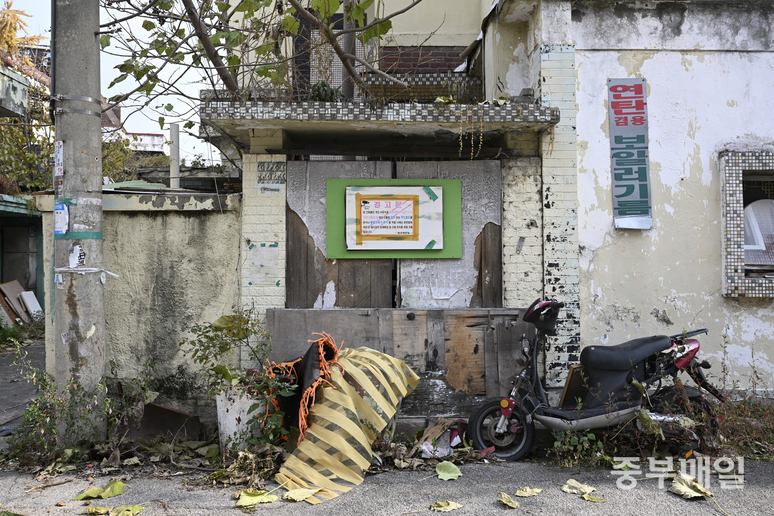▲ 24일 재개발이 예정된 청주시 서원구 무심천 인근 사직4구역 한 민가 앞 대문에 경고문이 부착되고 폐기물이 쌓여있다. /김성렬